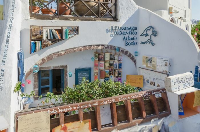Exterior de biblioteca aconchegante e grandioso com livros e plantas, exibindo um ambiente m&aacute;gico de livraria de todo o mundo.