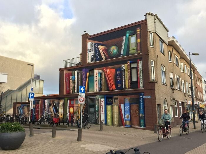 Building facade painted with giant, colourful books, creating a magical library and bookstore atmosphere in an urban setting.