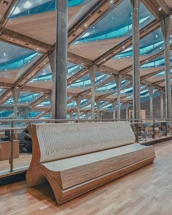 Bench shaped like an open book inside a modern, grandiose library with glass and metal architecture from around the world.