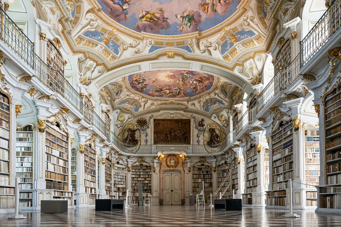 Grandiose library interior with ornate ceilings and tall bookshelves filled with books in a magical atmosphere.